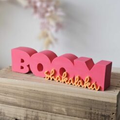 3D-gedruckter Schriftzug Boom Shakalaka in Pink und Orange auf Holzblock – DIY-Deko aus STL- und 3MF-Datei von The Vectorians