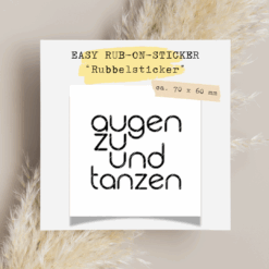 Rub-On Rubbelsticker mit dem Spruch „Augen zu und tanzen“ im Format 70 × 60 mm, platziert auf weißem Hintergrund mit Naturdeko